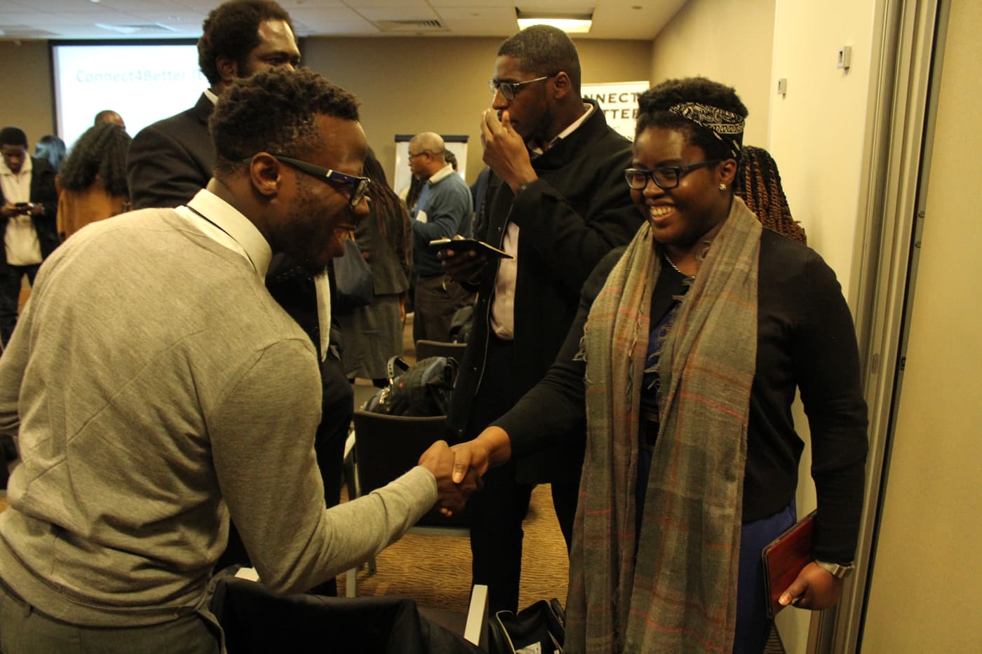 Two attendees shaking hands and laughing after a Cee4Bee panel