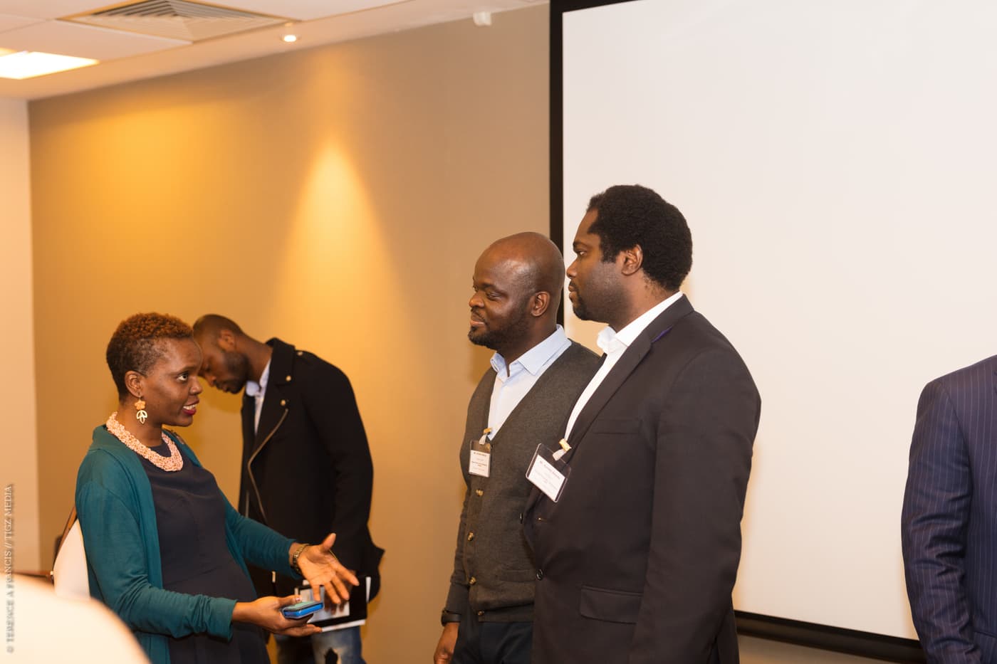 Attendees talking at the back of the room