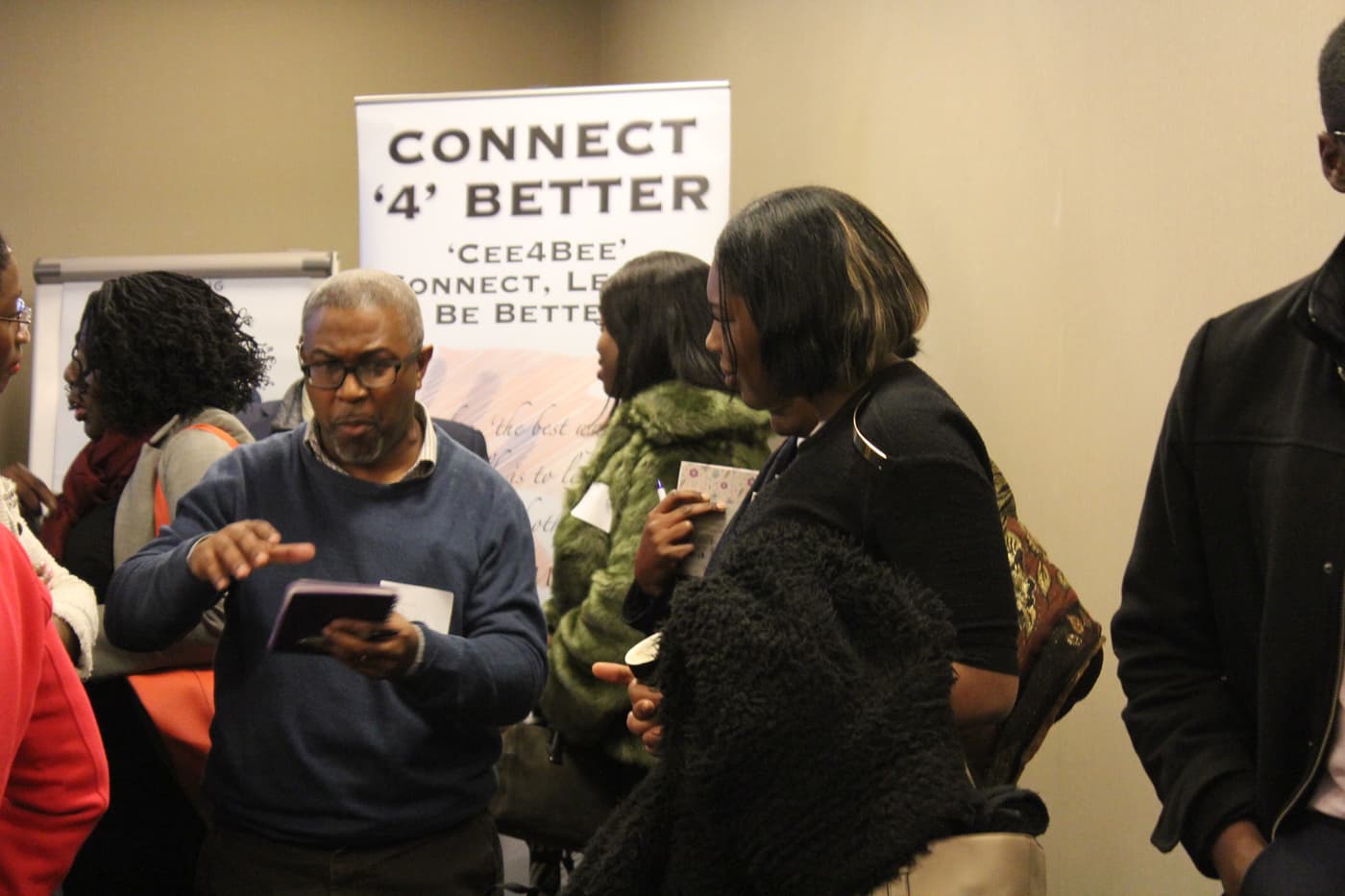 Attendees exchanging details in front of the Connect4Better banner