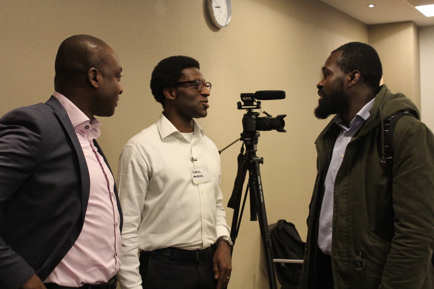 Three attendees talking beside the event camera