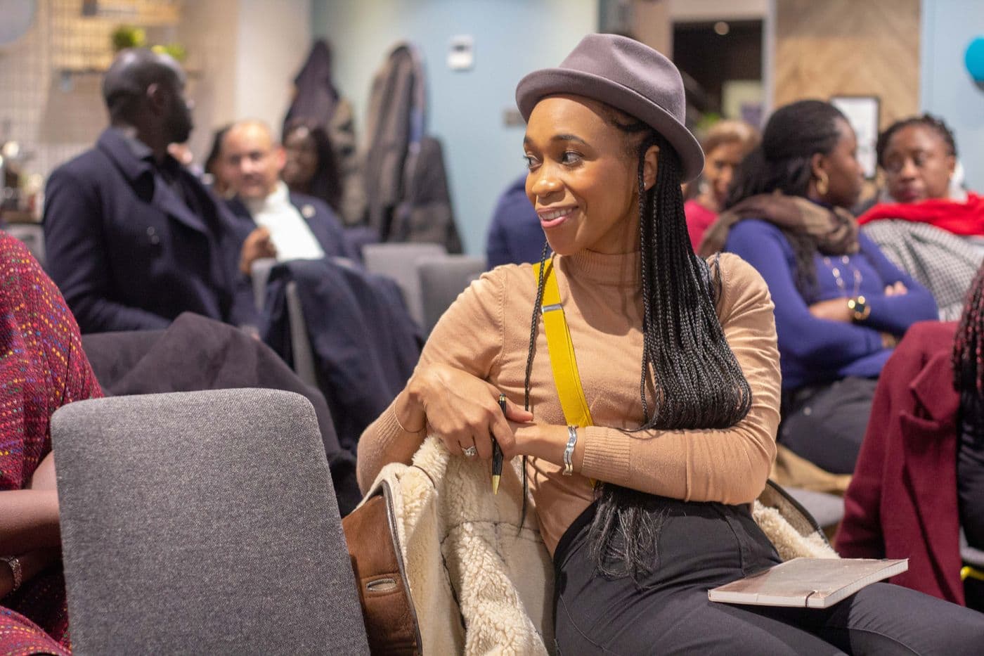 Attendees listening, one wearing a wide-brimmed hat