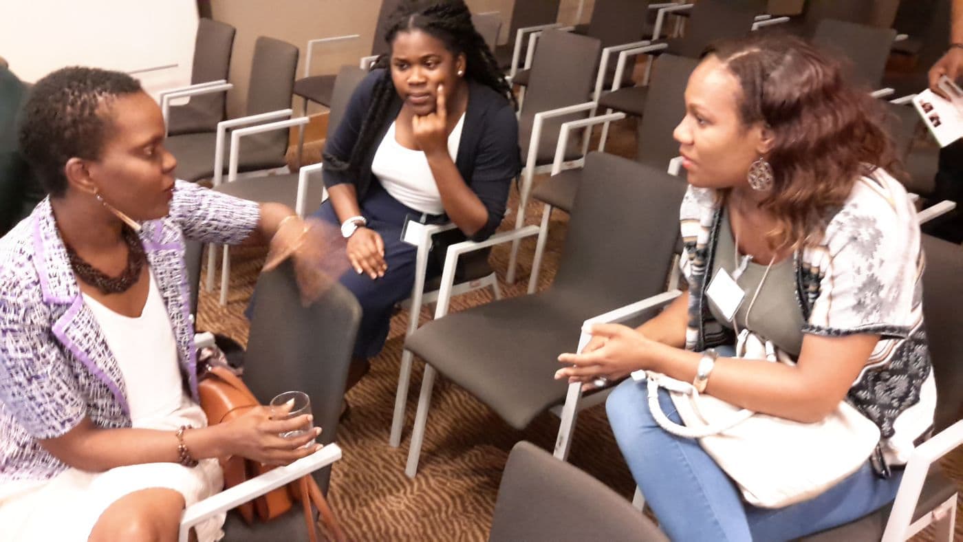 Two attendees talking across a row of chairs