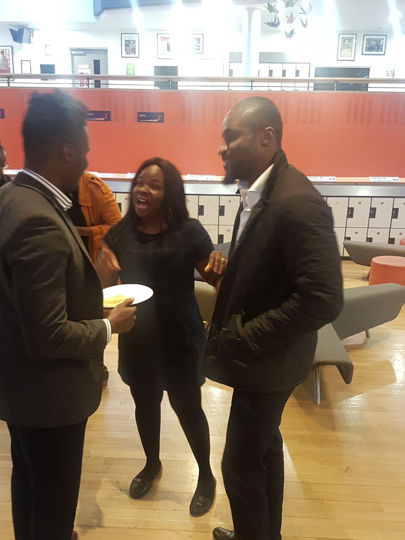 Three attendees talking over refreshments in the atrium