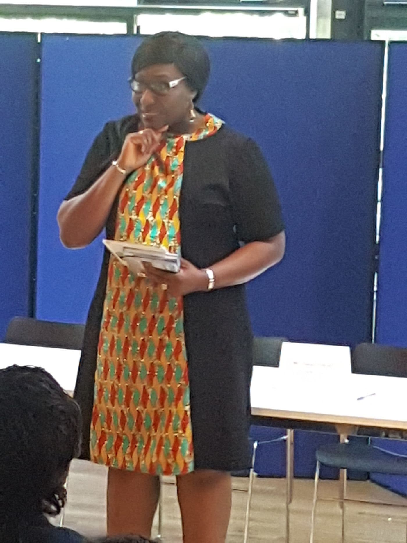 A speaker addressing the room, notes in hand