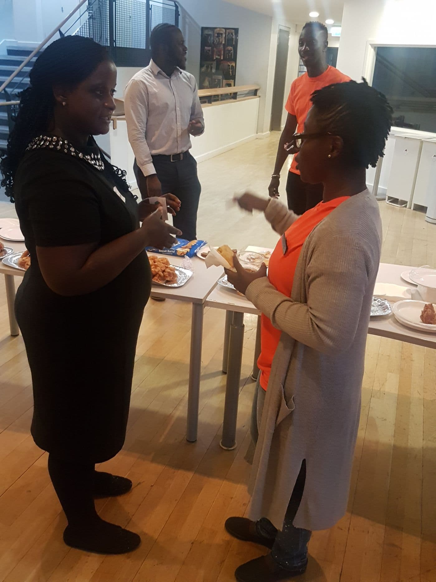 Two attendees in conversation beside the buffet