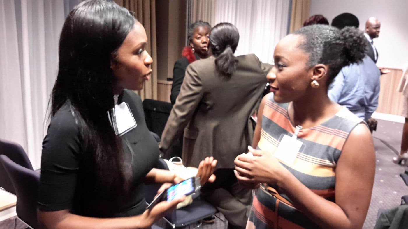 Two attendees talking, one showing something on a phone