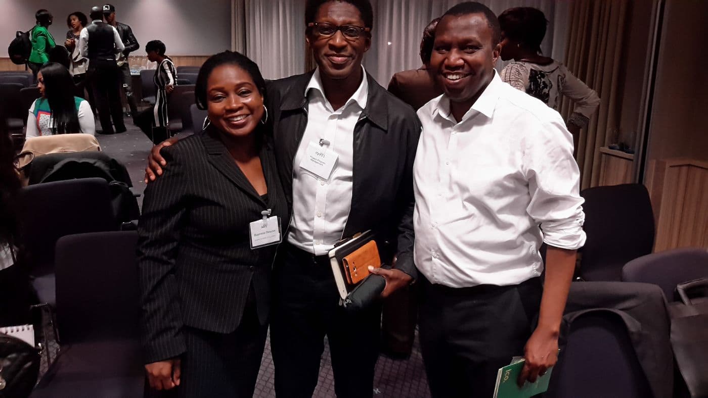 Three attendees together for a photograph, name badges on