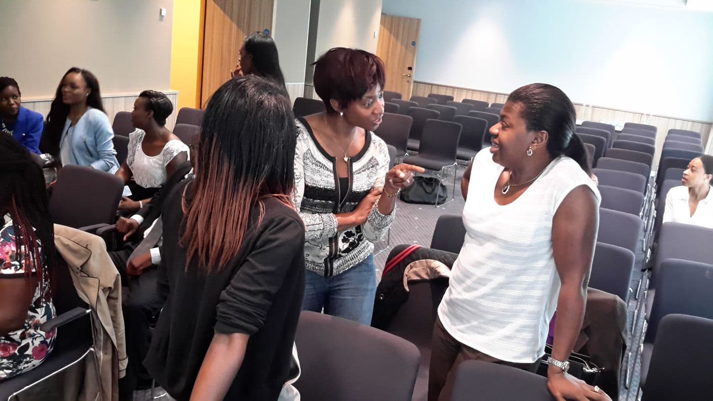 A group standing and talking between rows of chairs