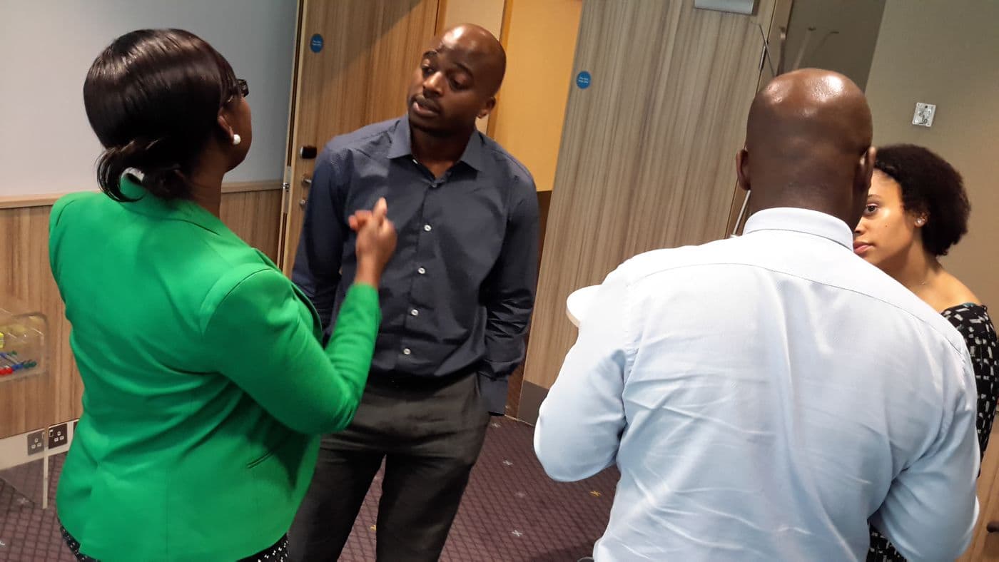 Three attendees in conversation, one gesturing