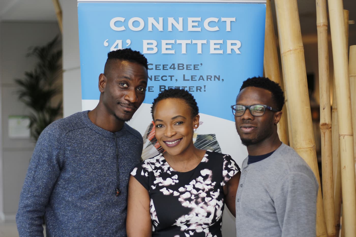 Three attendees in front of the Connect4Better banner