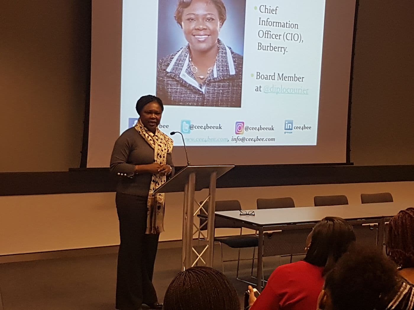 A speaker presenting beside a slide introducing a Chief Information Officer