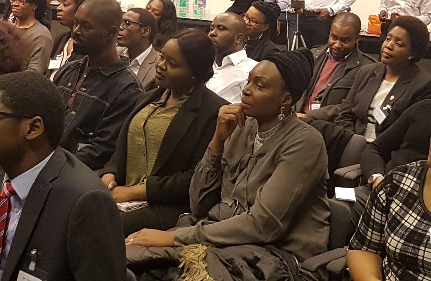 Attendees listening from the side of the room