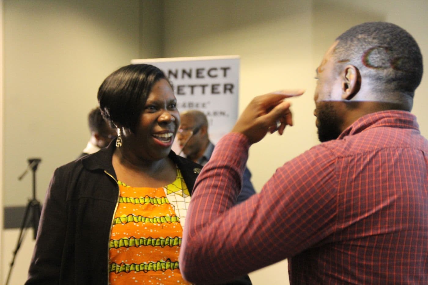 Two attendees in conversation in front of the banner