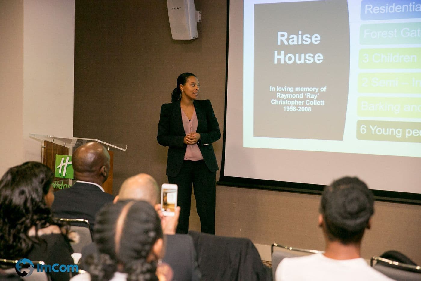 A speaker presenting a slide about Raise House