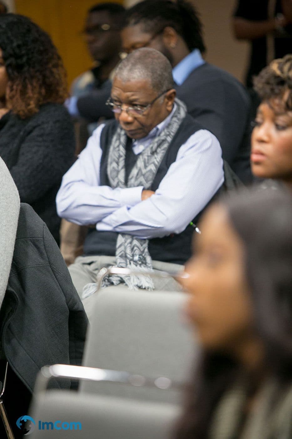 An attendee listening with arms folded