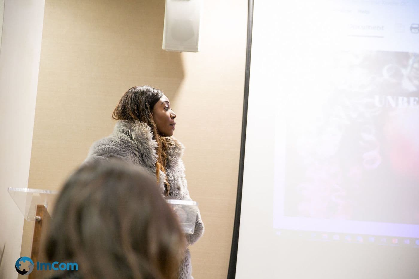 A speaker addressing the room beside the screen