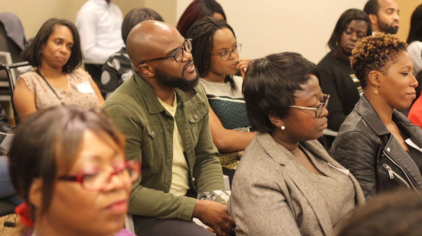 Attendees listening from the side of the room