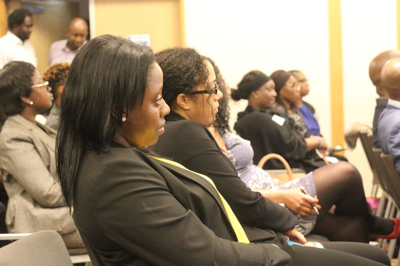 Attendees listening from the side of the room