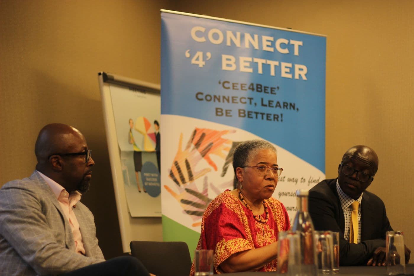 A speaker seated beside the Connect ’4’ Better banner